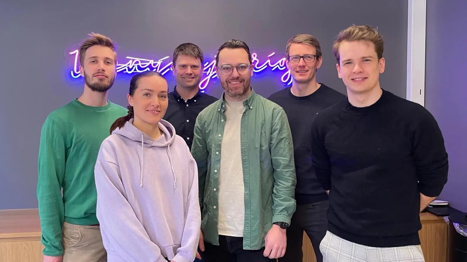 Seks personer fra eIDAS-teamet i Kantega står foran en vegg med et neonskilt